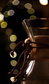 Close-up of a Chemex coffee maker with artistic bokeh lighting for a cozy ambiance.