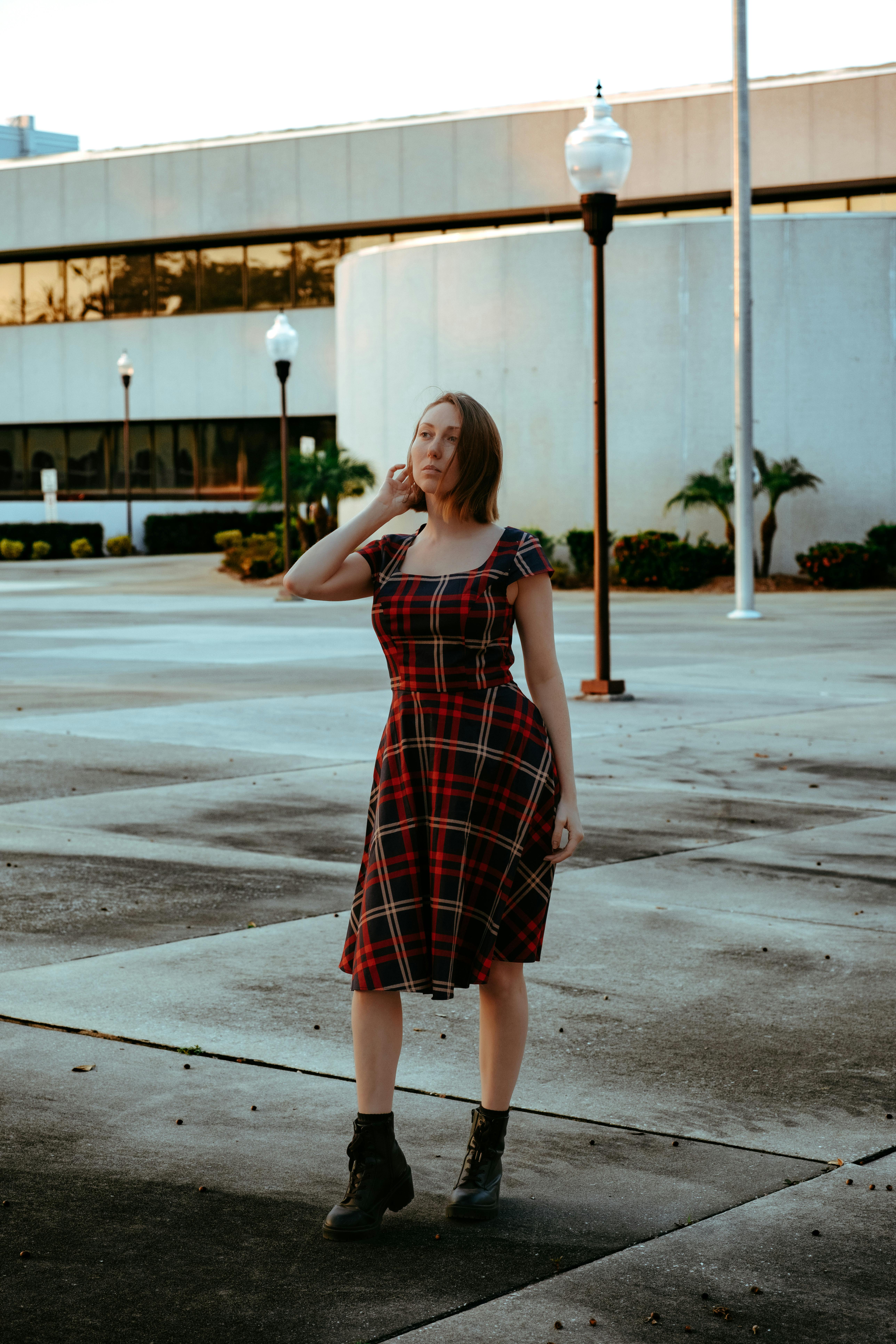 a woman in a red plaid dress is standing in front of a building