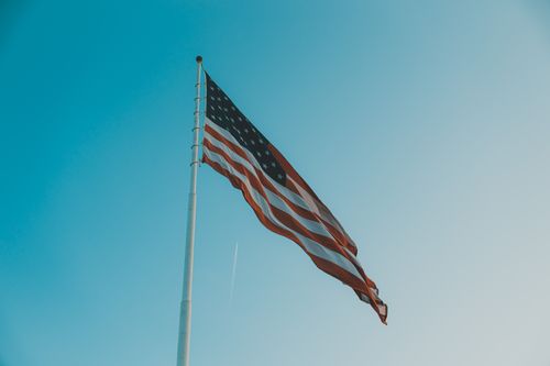 Free Low angle view of the American flag waving on a windy day against a clear blue sky. Stock Photo
