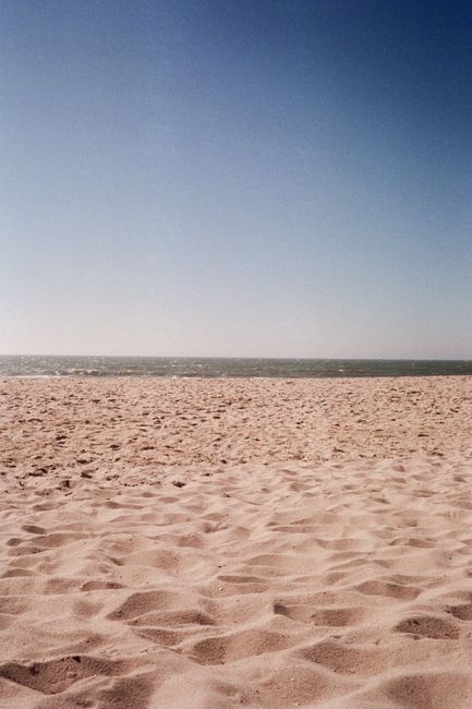 A serene view of the sandy beach and ocean under a clear blue sky in Esmoriz, Portugal.