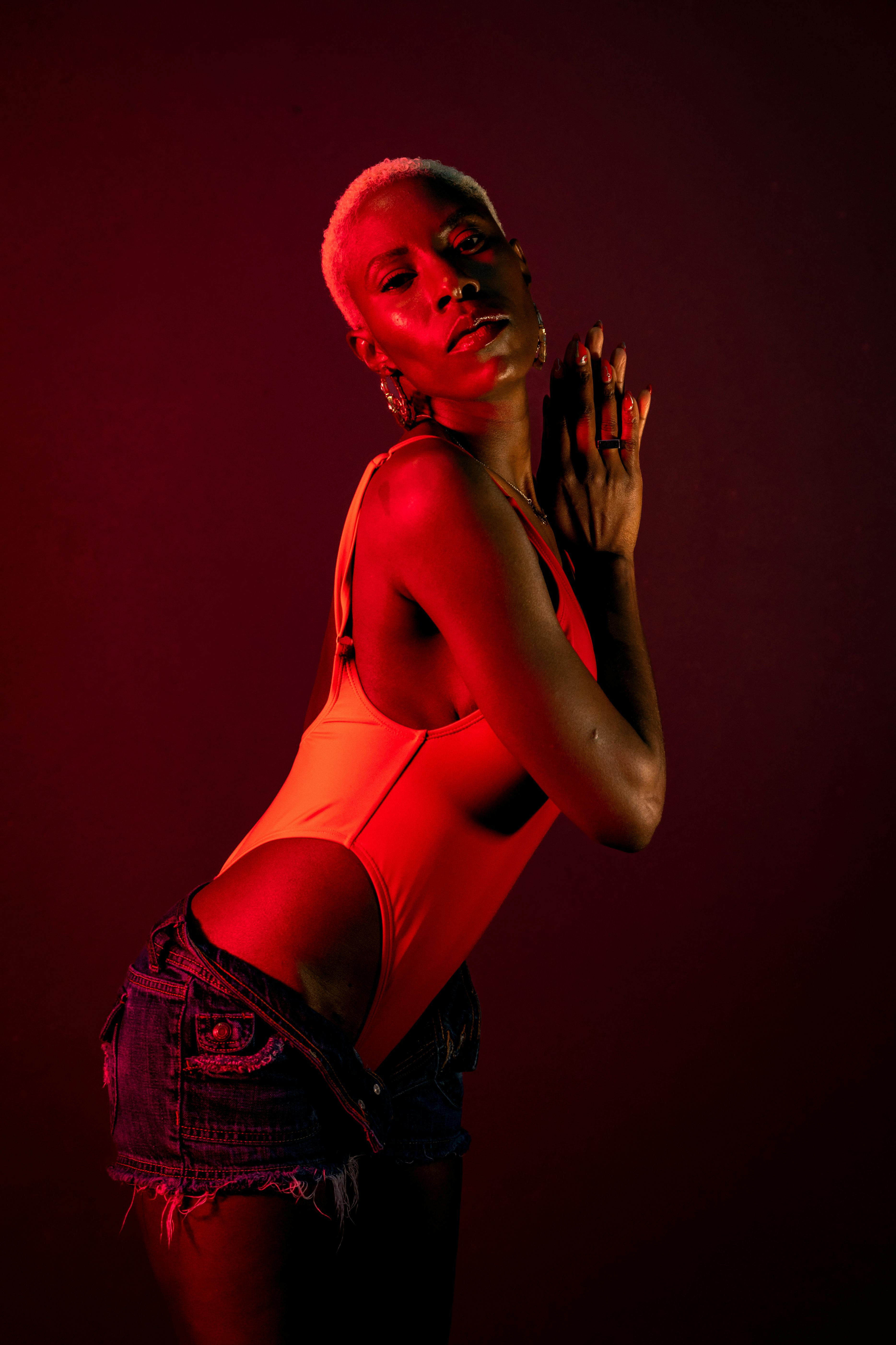 A captivating studio portrait of a woman posing in red lighting, exuding elegance.