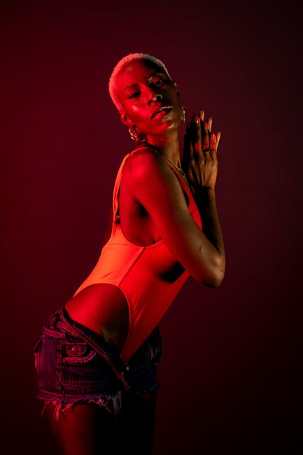 A captivating studio portrait of a woman posing in red lighting, exuding elegance.