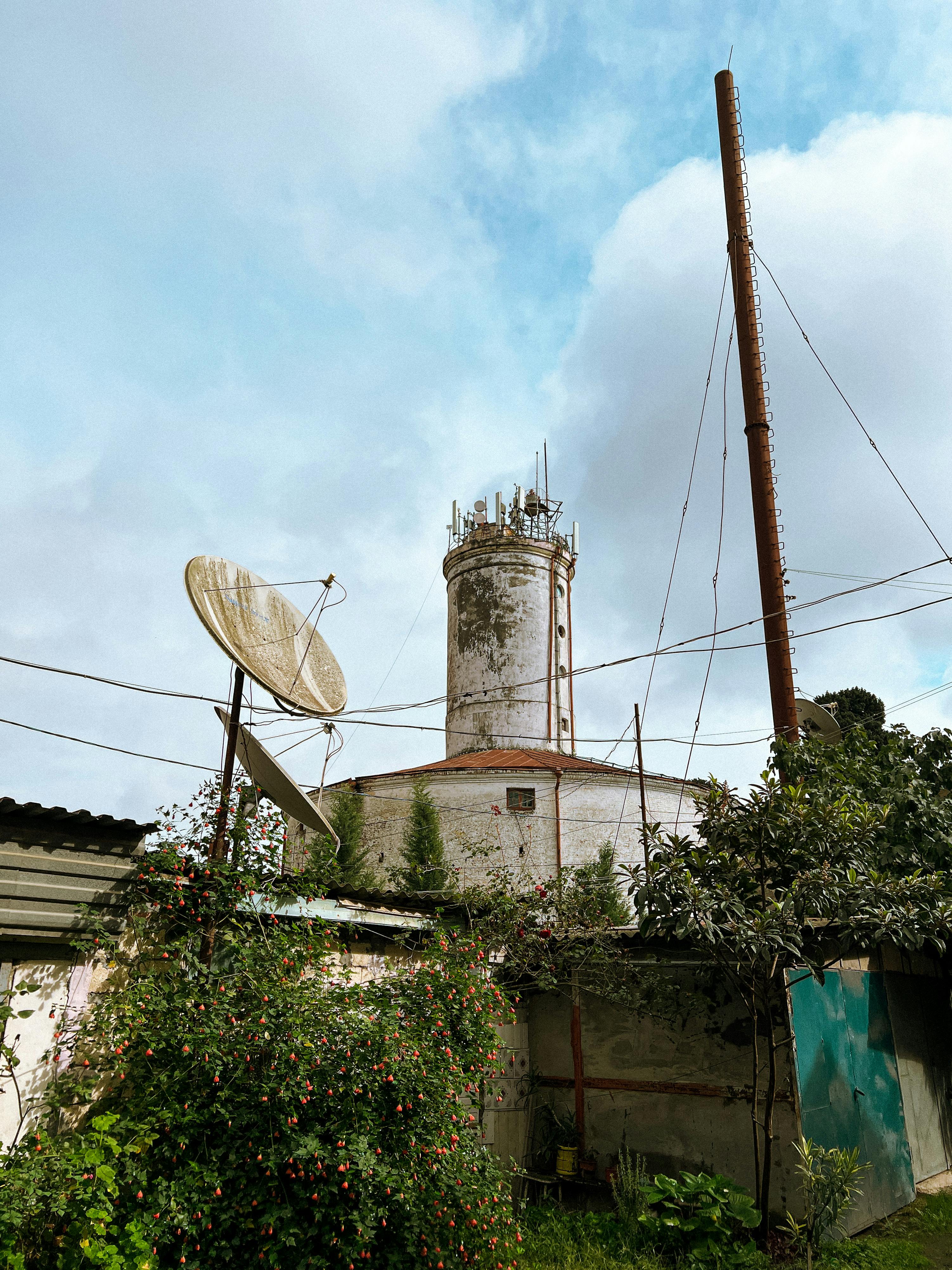 Image of a historical tower with satellite dish in Lankaran, Azerbaijan, amidst lush greenery.