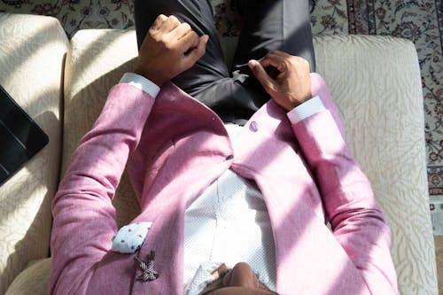 Free Man Wearing Pink Suit Jacket And Black Pants Sitting On Sofa Stock Photo