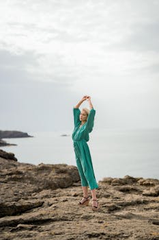 Fashion model in a green dress poses by the rocky coast of Rumelifeneri, İstanbul.