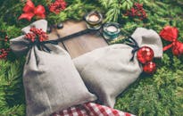 圣诞主题礼品袋周围装饰着节日饰品、松枝和蜡烛