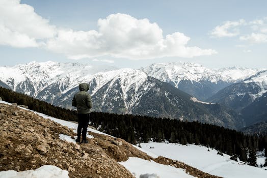 A solitary hiker admires the stunning snow-covered mountains in Rize, Turkey.