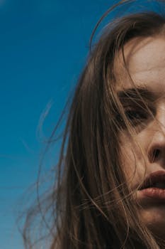 A close-up shot of a woman with long brown hair against a clear blue sky in Istanbul.