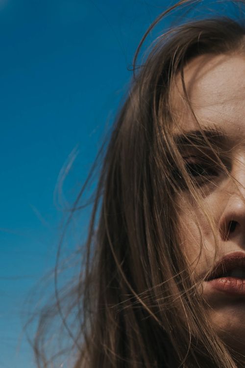 Free A close-up shot of a woman with long brown hair against a clear blue sky in Istanbul. Stock Photo