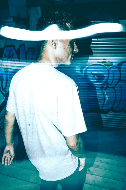 Free Dynamic portrait of a man in streetwear with vibrant graffiti backdrop. Stock Photo