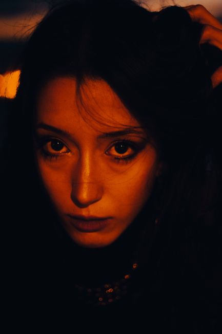 Dramatic close-up portrait of a woman with intense eyes and warm lighting.