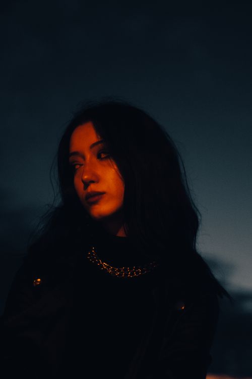 Free An evocative portrait of a woman in low light, featuring dark tones and a pensive mood. Stock Photo