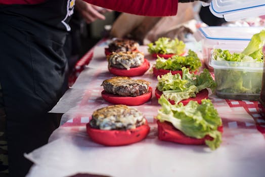 Delicious gourmet burgers with unique red buns being prepared on a checkered table.