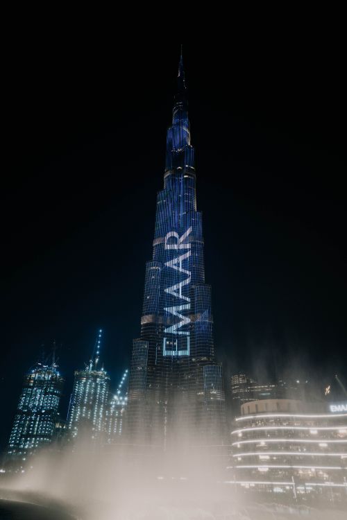 Free Explore the iconic Burj Khalifa towering over Dubai's cityscape at night, featuring vibrant lights. Stock Photo