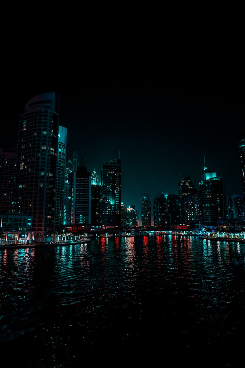 A city skyline at night with a river and buildings · Free Stock Photo