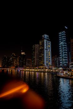 Night view of Dubai Marina's illuminated skyline reflecting on the water.