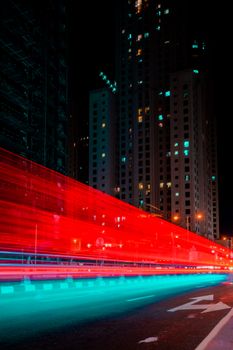 Vibrant night view of Dubai's skyscrapers with dynamic red and blue light trails.