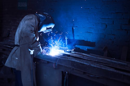 Homem Usando Capacete De Soldagem, Metal De Solda Próximo à Parede De Tijolo Cinza