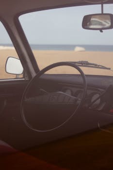 Inside view of a vintage car with a beach backdrop in Algiers, Algeria.
