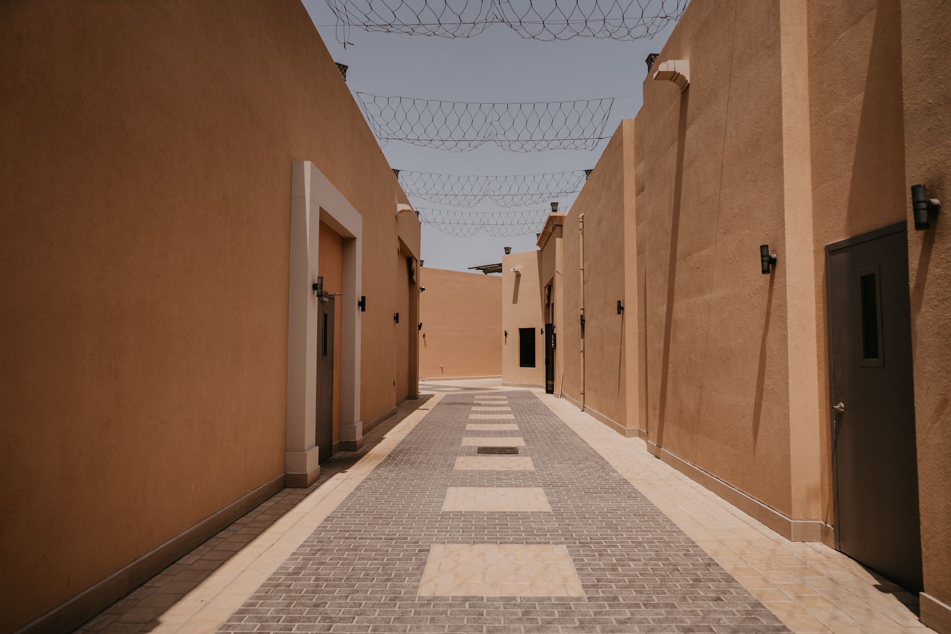 A serene, narrow alleyway flanked by sandstone buildings in Dubai under a clear sky.