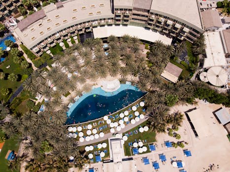 Captivating aerial view of a luxury hotel's pool surrounded by lush palm trees in Dubai.