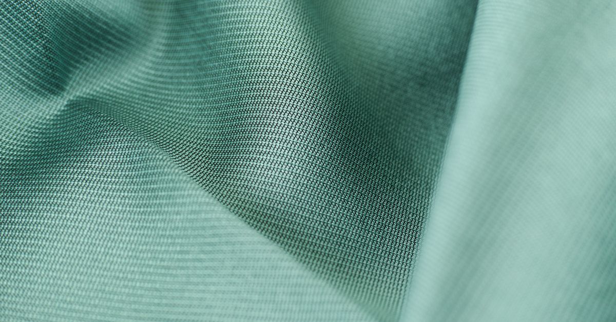 Detailed close-up shot of smooth green silk fabric texture showcasing softness and elegance.