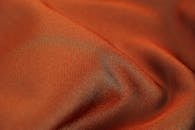 特写捕捉柔软光滑的橙色面料纹理，展现丝滑的光泽