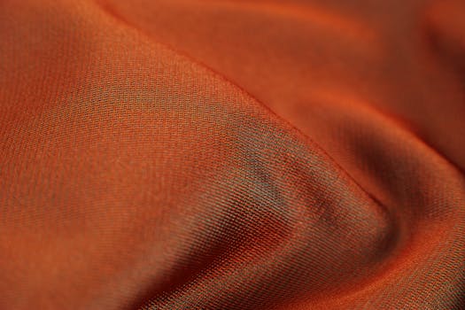 特写捕捉柔软光滑的橙色面料纹理，展现丝滑的光泽