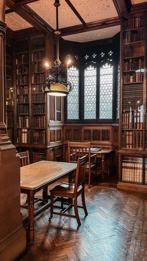 Free Sophisticated vintage library interior with ornate wooden bookshelves and tables. Stock Photo