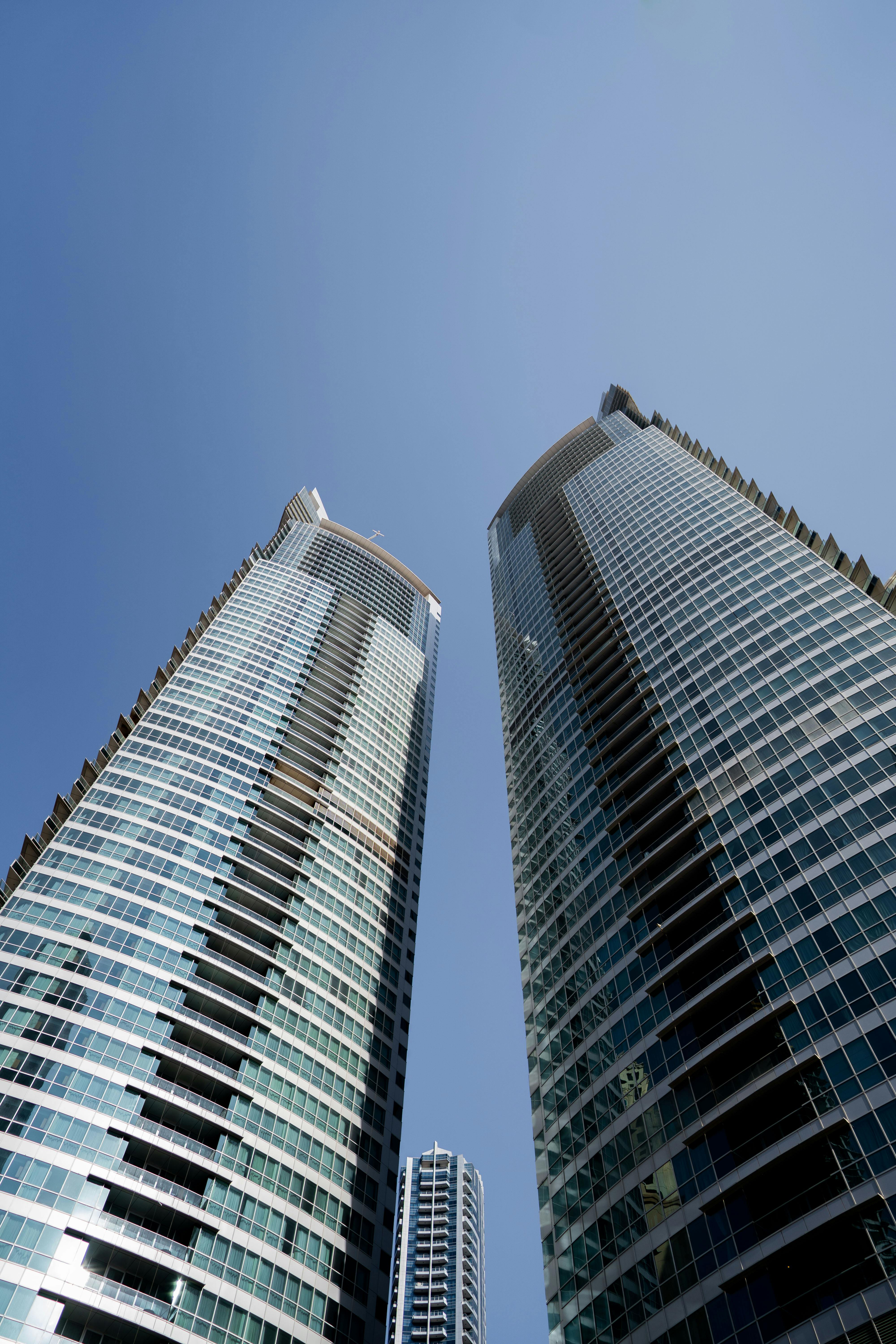 two tall buildings with glass windows and a blue sky