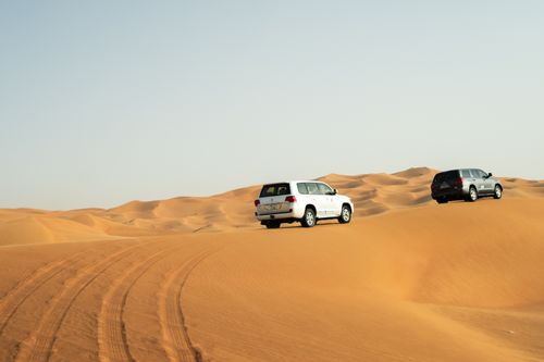 Free Two SUVs navigate the stunning sand dunes of Dubai, capturing adventure in the Arabian desert. Stock Photo