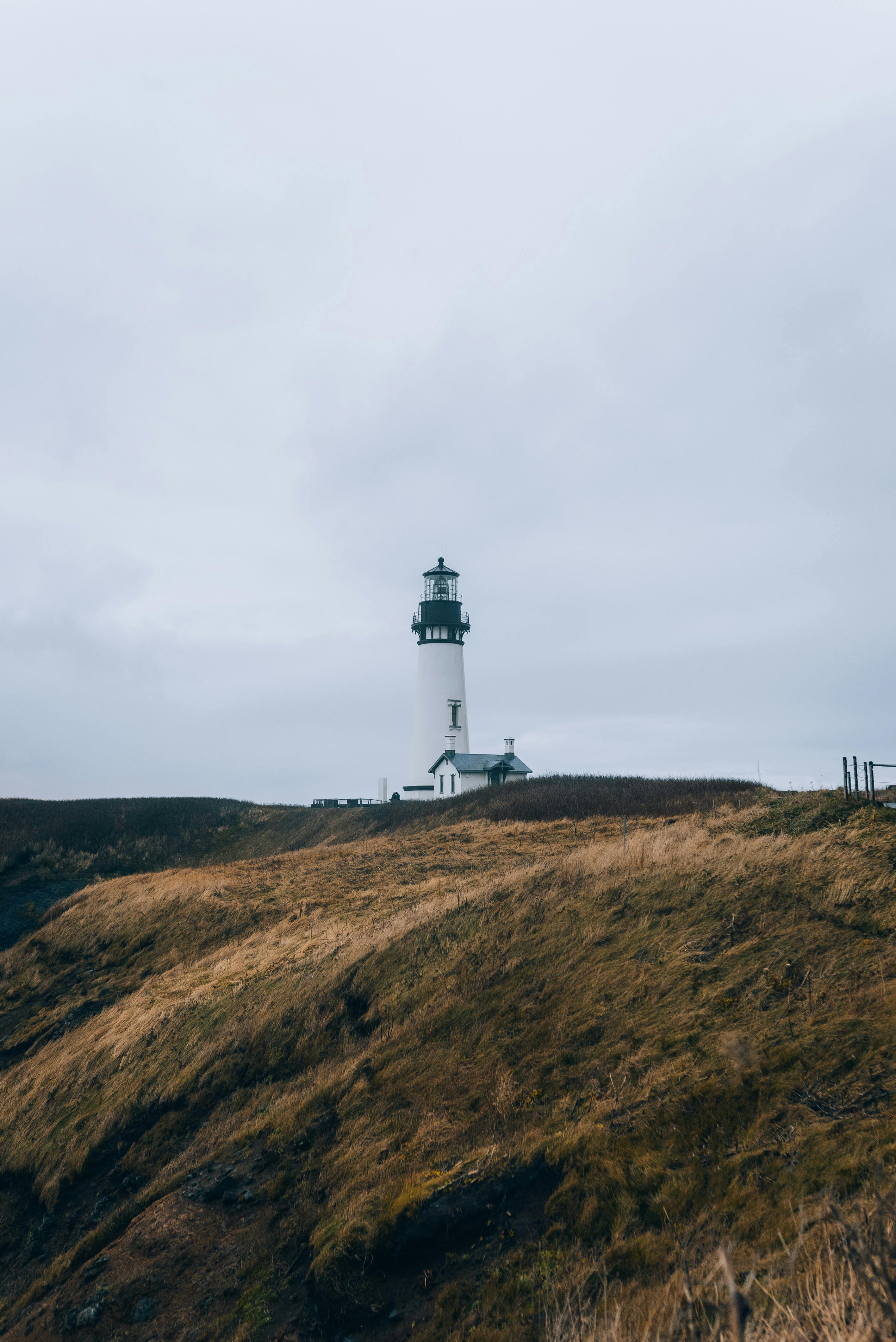 a lighthouse on a hill with a cloudy sky