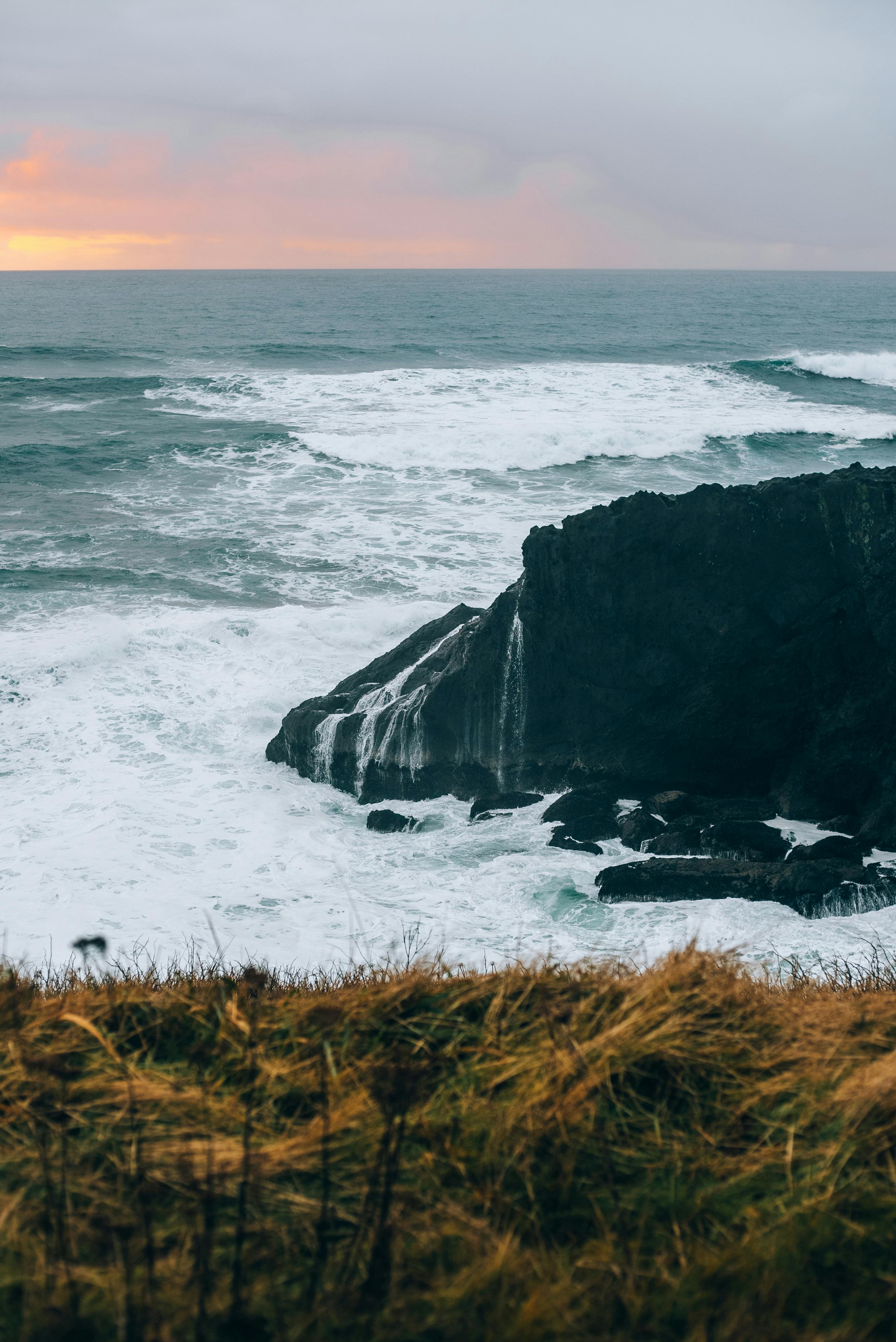 a sunset over the ocean with a rocky cliff