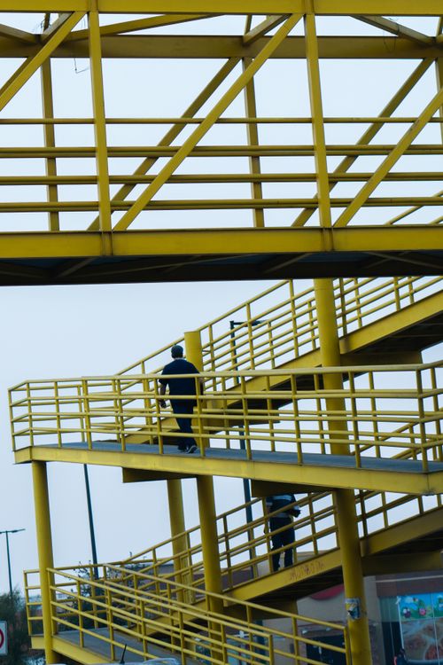Free Vertical view of a yellow metal pedestrian walkway with people, showcasing urban infrastructure design. Stock Photo