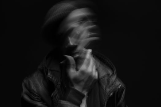 A dramatic black and white portrait depicting blurred motion, creating an abstract and mysterious effect.