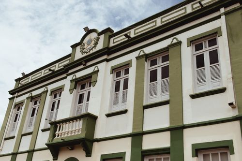 Free Low angle view of a classic building with ornate green facade and shuttered windows under a clear sky. Stock Photo