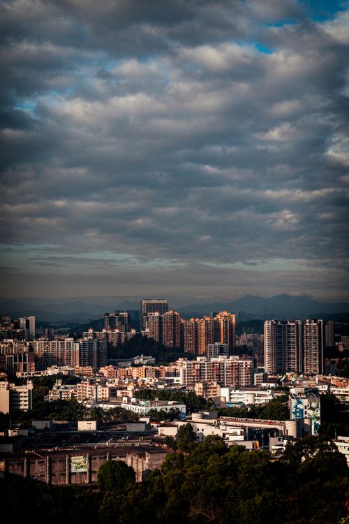 Free A bustling cityscape with tall buildings under a dramatic cloudy sky, showcasing urban life. Stock Photo