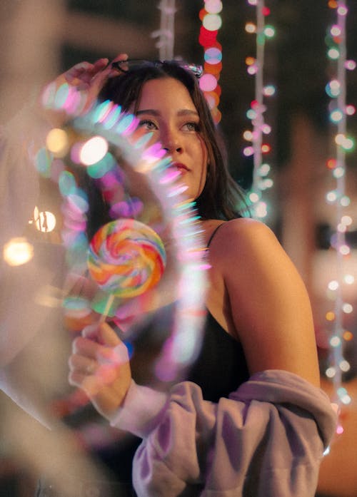 A Woman in Black Tank Top Holding a Lollipop