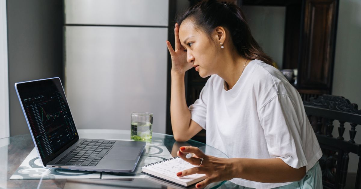 person staring at stock chart on laptop with stressed expression