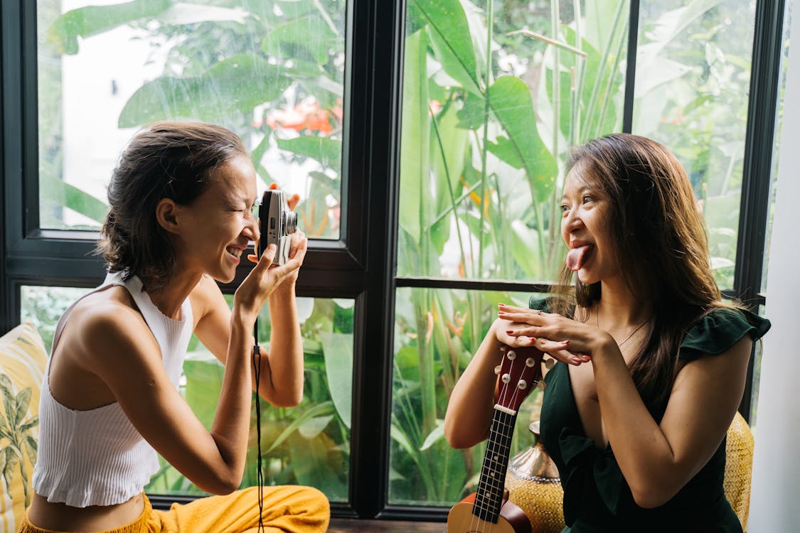 Woman Taking a Picture of Another Woman with a Film Camera 