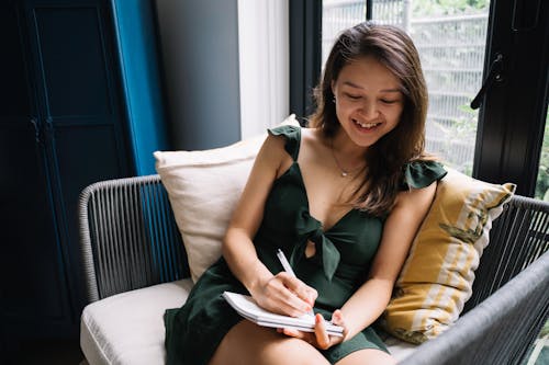 Young Woman Sitting on a Couch with a Notepad 
