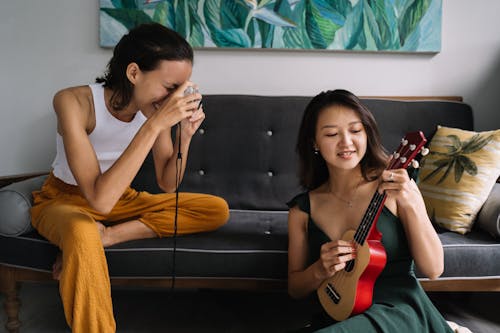 Woman Playing on a Ukulele and the Other Woman Taking a Picture