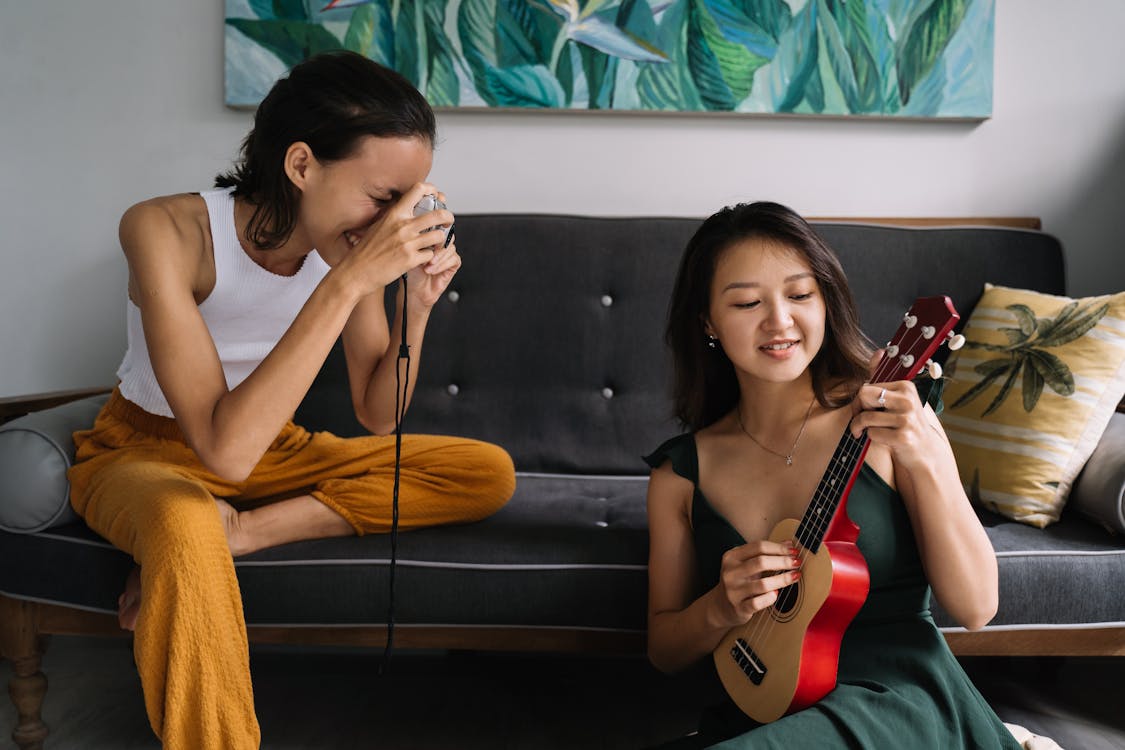 Woman Playing on a Ukulele and the Other Woman Taking a Picture