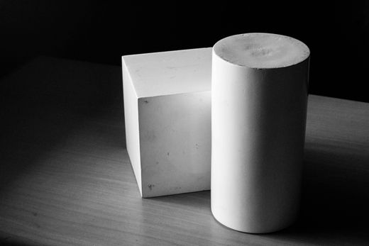A cube and cylinder on a wooden table — Photo by Jason Yaranon on Pexels