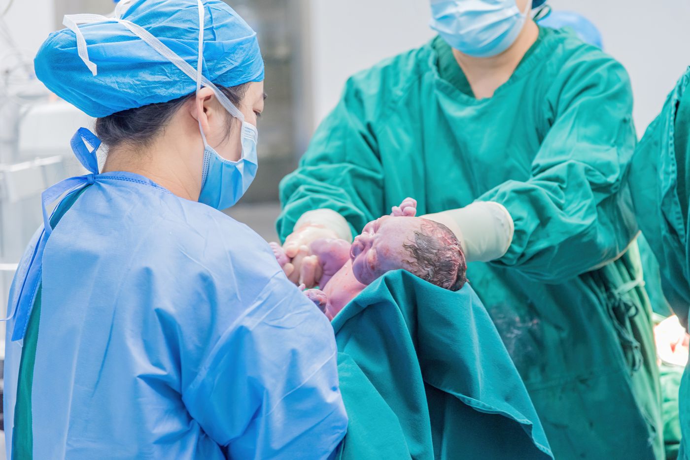Clinicians holding a newborn shortly after birth