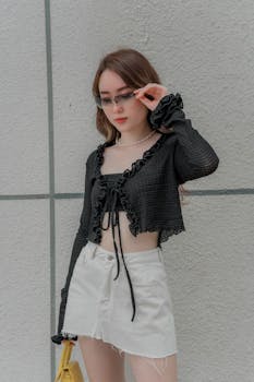 Fashionable woman in sunglasses posing against a concrete wall.