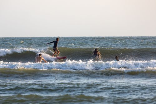 Free Group of surfers riding waves with surfboards in clear ocean water during daylight. Stock Photo