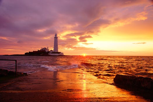 Breathtaking sunrise over a lighthouse by the sea, casting warm colors in the sky and reflecting on the water.