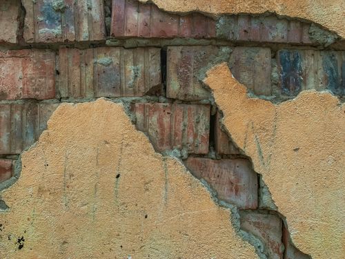 Free Close-up of a weathered brick wall with peeling plaster, showcasing textured decay. Stock Photo