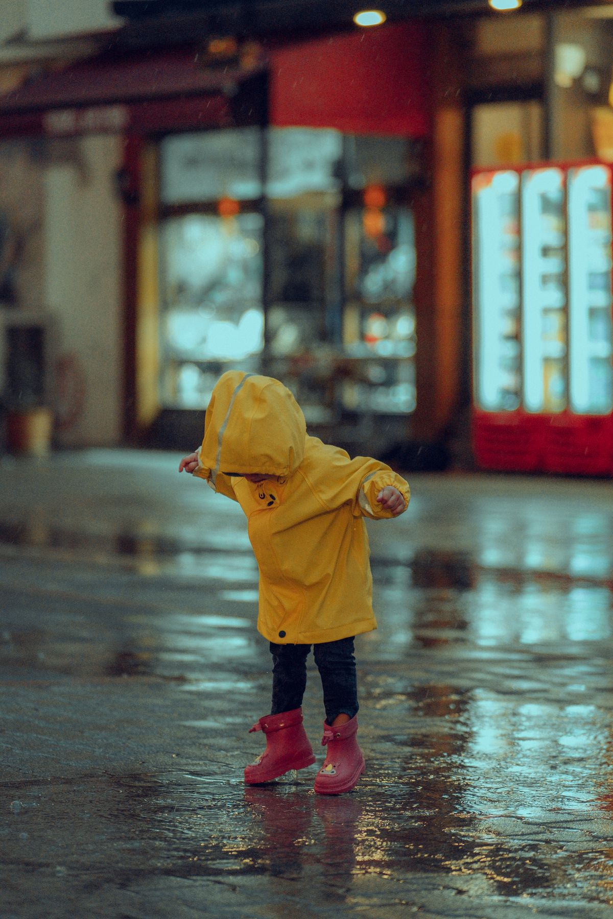 Child in a yellow raincoat on a rainy city street